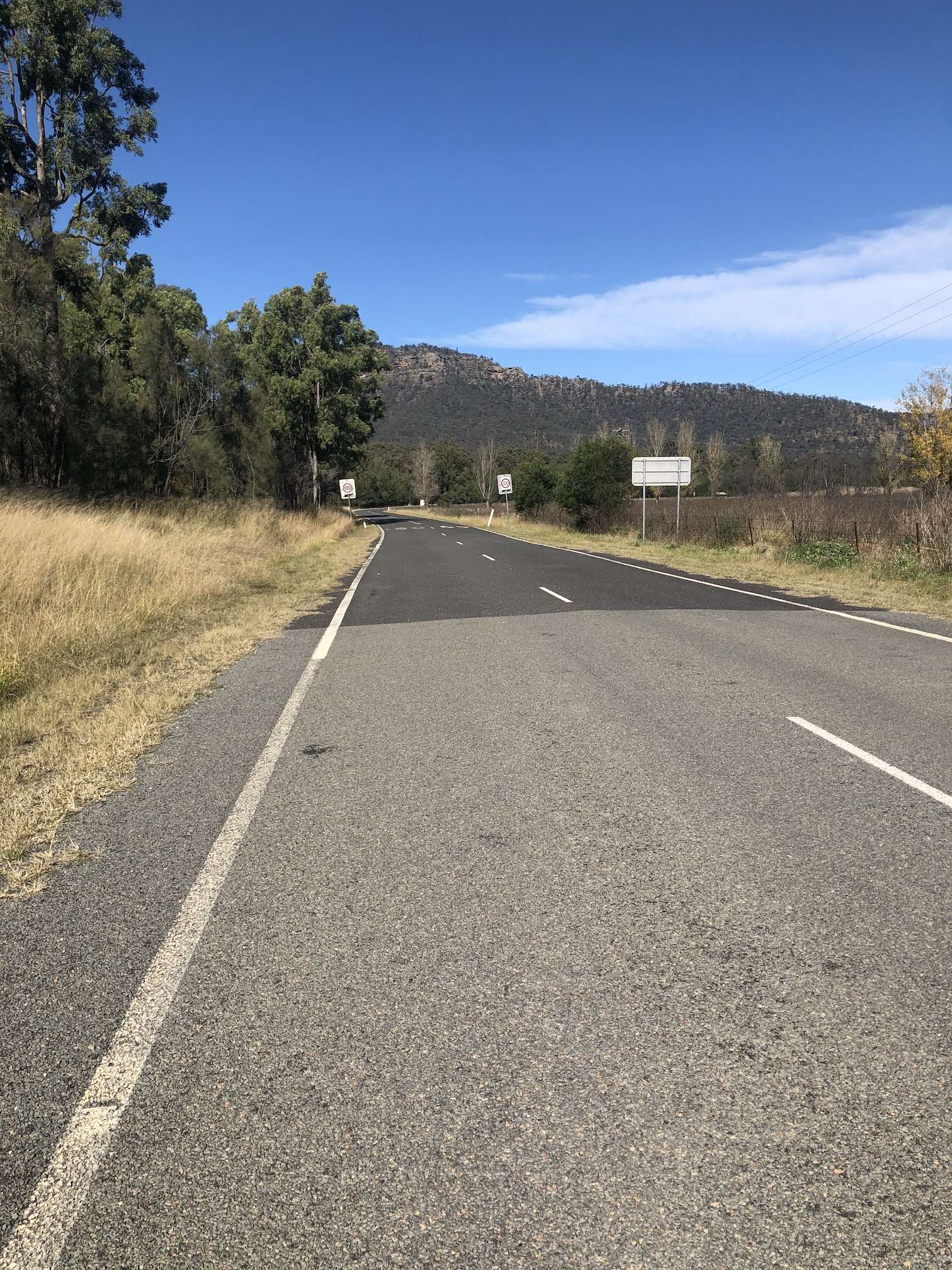 Sandstone formation in the distance, a road with little shoulder.