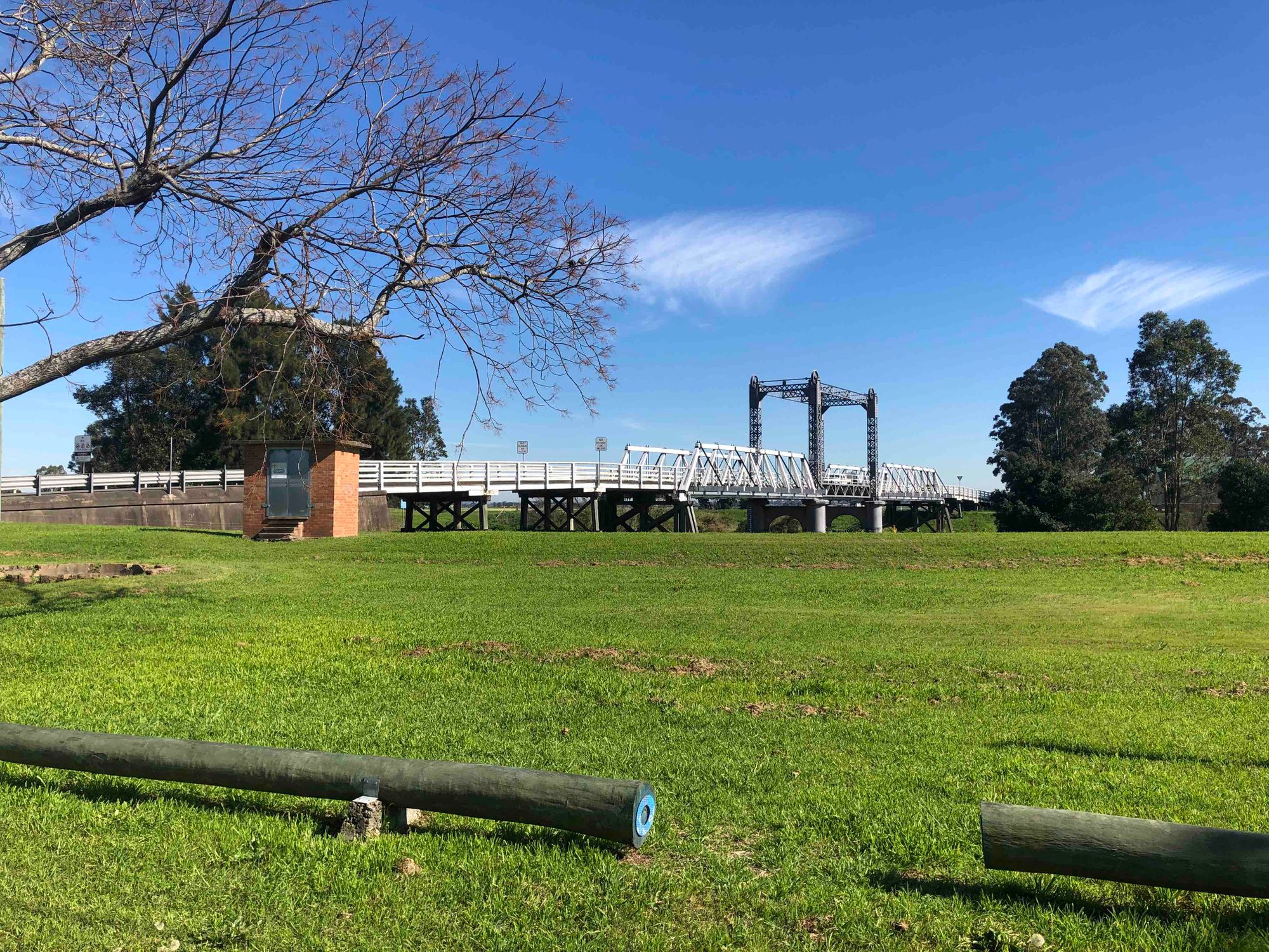 A truss bridge with raisable deck, against a blue sky and green grass.