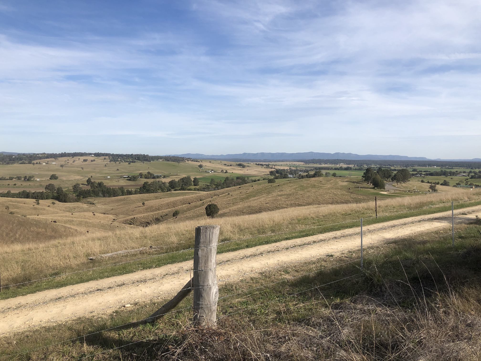 View over green valley, with mountains in the far distance.