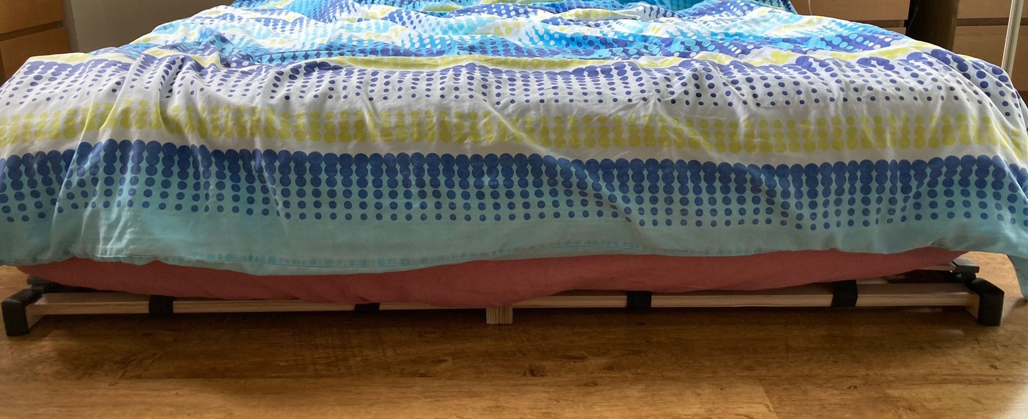 Foot of the bed; you see a tiny frame under the mattress sticking out, with black pads covering corners.