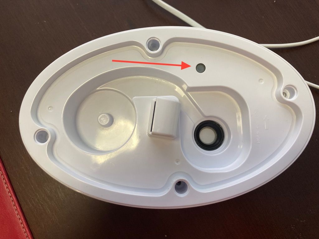 Lower half of humidifier; showing a button the water tank can depress, and the ultrasonic speaker membrane.